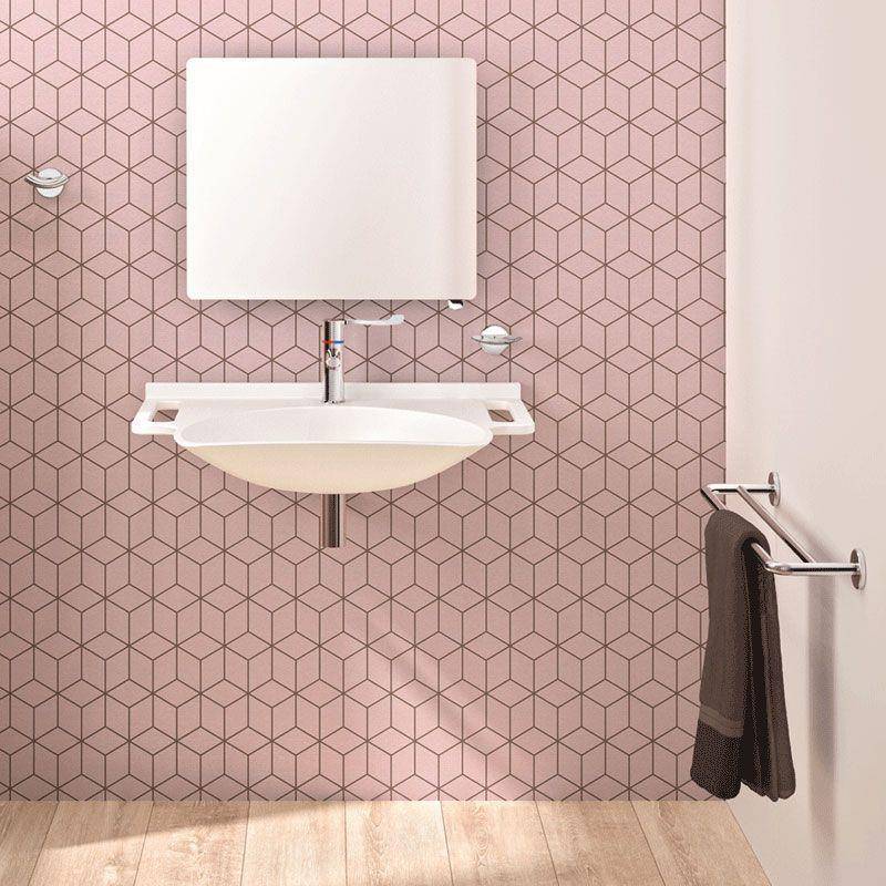 Modernes Badezimmer mit wandmontiertem Waschbecken und Spiegel an einer rosa geometrisch gefliesten Wand, Handtuch hängend auf einem seitlichen Handtuchhalter.