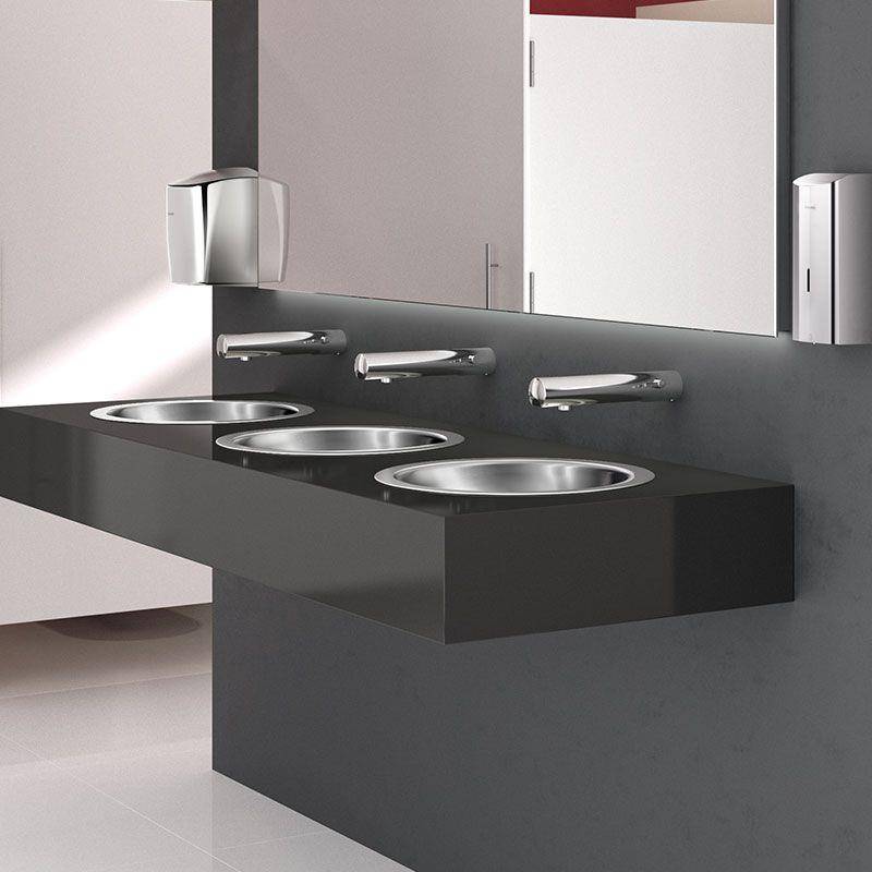 Modernes Badezimmerregal mit drei Edelstahlwaschbecken in einer dunklen Arbeitsplatte, jeweils mit einer wandmontierten Armatur und einem Spiegel darüber.