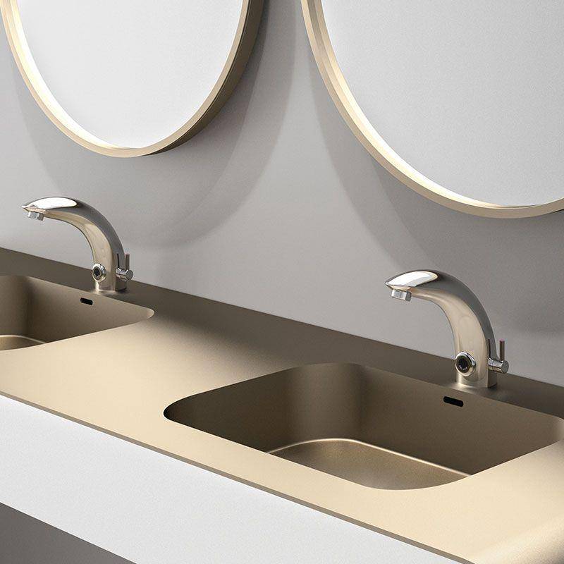 Modernes Badezimmer-Waschtisch mit zwei Edelstahlarmaturen und eingelassenen Waschbecken unter runden Spiegeln auf einem beige und weißen Waschtisch.