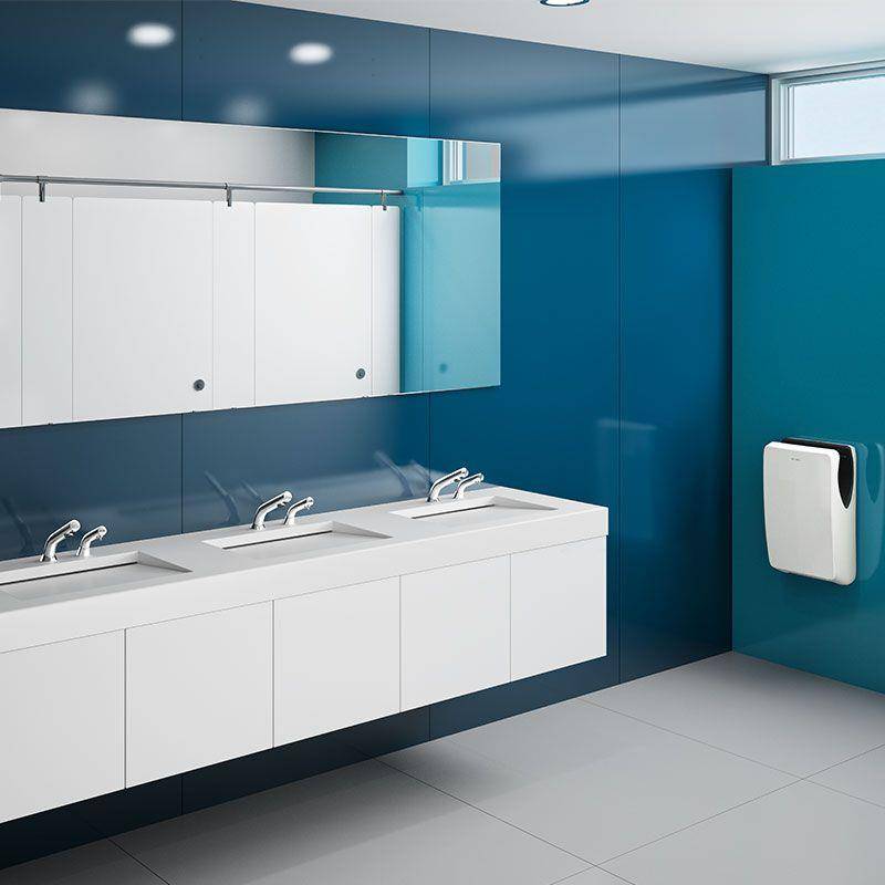 Modernes öffentliches Badezimmer mit blauen Wänden, weißen Waschbecken und Schränken, großem Spiegel und einem wandmontierten Papierhandtuchspender.