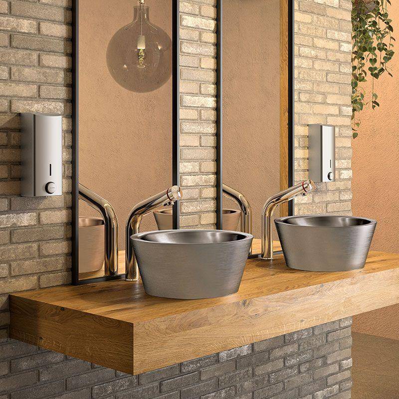 Zwei moderne Aufsatzwaschbecken mit Chromarmaturen auf einer Holzbadezimmerablage, vor einer Ziegstein- und beige Wand mit Spiegeln und Pendelleuchten.