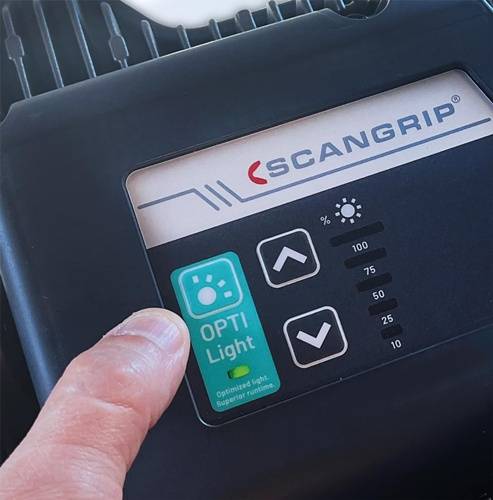 Nahaufnahme einer Hand, die die Helligkeitseinstellungen an einem Scangrip-Gerät anpasst, wobei ein Display Prozentoptionen von 0 bis 100 zeigt.