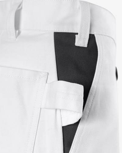 Nahaufnahme eines weißen Kleidungsstücks mit einer Tasche und einem Riemen, das ein kontrastierendes schwarzes Stoffdetail aufweist.