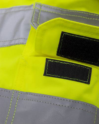 Eine Nahaufnahme einer leuchtend gelben und grauen Warnweste aus reflektierendem Material mit schwarzen Klettverschlüssen, die den hochsichtbaren Stoff in den Vordergrund stellt.