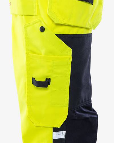 Nahaufnahme einer Tasche und eines Knopfes an einer signalgelben Arbeitshose, mit schwarzem Stoffdetail.