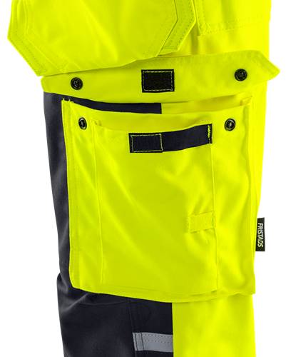 Eine helle gelbe Kleidung mit einer Tasche und schwarzen Knopfdetails, die einen industriellen oder Arbeitskleidung-Stil verkörpert.