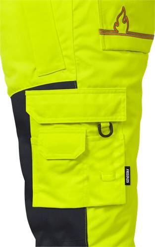 Nahaufnahme einer signalgelben Arbeitshose mit schwarzen Akzenten und mehreren Taschen, die die Funktionalität für Utility- oder Bauarbeiten demonstriert.