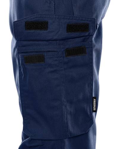 Marineblaue Arbeitshose mit schwarzen Klettpatches und einem sichtbaren 'FRISTADS' Etikett an der Seitentasche.