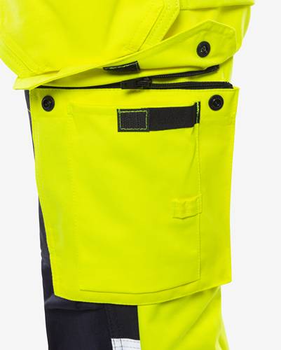 Eine Nahaufnahme eines signalgelben Kleidungsstücks mit einem schwarzen Reißverschluss und Taschen, das für Sicherheitsarbeitskleidung konzipiert ist.
