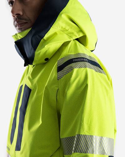 Eine Person, die eine Warnschutzjacke in leuchtendem Gelb mit reflektierenden Streifen trägt.