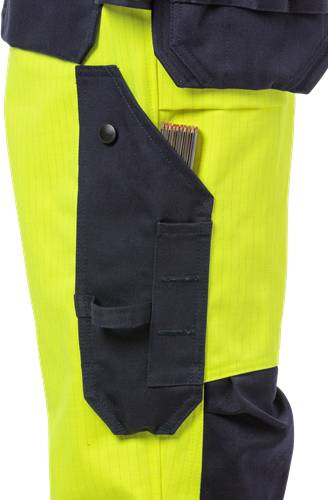 Eine Nahaufnahme der Neon-Gelben Sicherheitshose eines Arbeiters mit einer angehängten Tasche, in der mehrere farbige Buntstifte stecken.