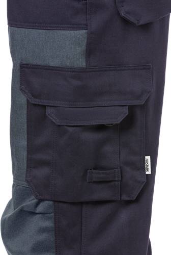 Eine Nahaufnahme einer dunkelblauen Hosen-Tasche mit Klappe und einem kleinen Logo-Etikett an der Seite. Die Tasche befindet sich auf einem zweifarbigen Stoffhintergrund.