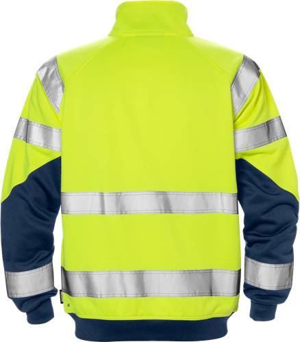 Eine Person, die von hinten gesehen wird, trägt eine Sicherheitsjacke in signalgelb und blau mit reflektierenden Streifen vor einem schwarzen Hintergrund.
