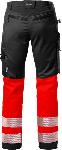 Eine Person, die eine schwarze und rote Hose trägt, die sich für Outdoor- oder Bauarbeiten eignet und sich auf Haltbarkeit und Schutz konzentriert.