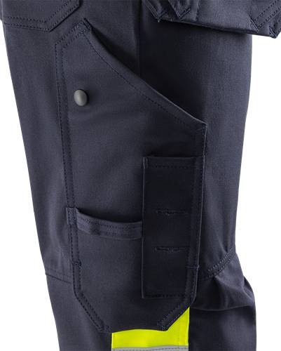 Nahaufnahme einer Arbeitshose in Marineblau mit einer Druckknopftasche und Stifthaltern, die deren Funktionalität und Design hervorhebt.
