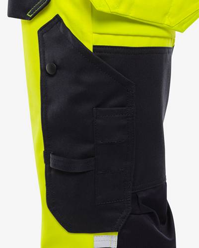 Helle gelbe und schwarze Tasche an einer Arbeitsjacke mit mehreren Fächern und einem Knopfverschluss, konzipiert für Funktionalität und Sichtbarkeit.
