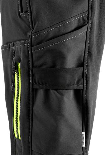 Detailaufnahme einer schwarzen Hose mit einem leuchtend gelben Reißverschluss und mehreren Taschen, die die funktionalen Designmerkmale des Kleidungsstücks hervorheben.