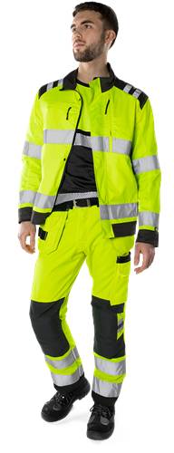 Eine Person, die eine leuchtend gelbe Warnschutzjacke und -hose trägt, die für die Sicherheit bei schlechten Sichtbarkeitsbedingungen konzipiert ist.