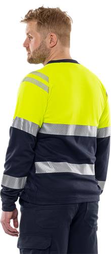 Eine Person trägt eine Warnschutzweste mit reflektierenden Streifen, was einen Fokus auf Sicherheit in einem Arbeitsumfeld anzeigt.