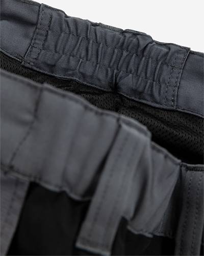 Nahaufnahme des Bunds einer dunkel gefärbten elastischen Shorts, die gerafftes Gewebe und Stickdetails zeigt.