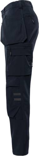 Person trägt schwarze Hose mit Taschen, steht vor einem schwarzen Hintergrund.