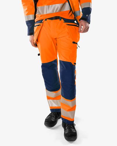 Eine Person trägt hochsichtbare orange und marinefarben Arbeitshose mit reflektierenden Streifen, die für die Sicherheit in industriellen oder Baubereichen entwickelt wurde.
