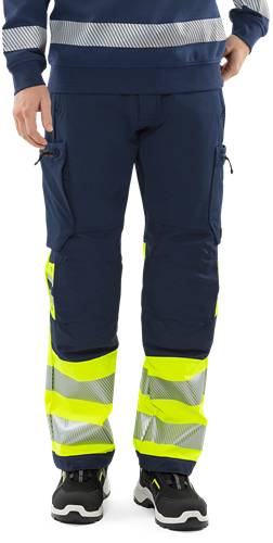 Person trägt dunkelblaue Arbeitskleidung mit gelben reflektierenden Sicherheitsstreifen, was auf einen Fokus auf Arbeitsplatzsicherheit oder Bauarbeiten hindeutet.