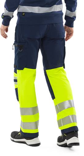 Eine Person, die eine navy-blaue und leuchtend gelbe Warnschutz-Arbeitshose trägt.