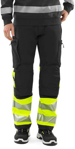 Person, die schwarze und gelbe Warnschutzhose mit reflektierenden Streifen trägt.