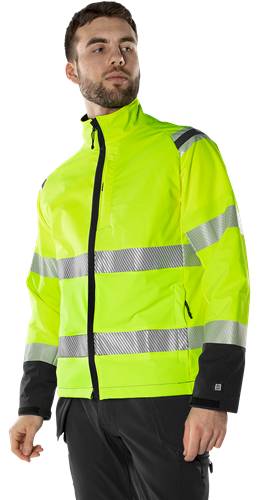 Eine Person, die eine hochsichtbare gelbe Jacke mit reflektierenden Streifen trägt, die für die Sicherheit bei schlechten Lichtverhältnissen konzipiert ist.