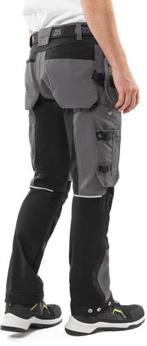 Eine Person, die dunkle Hosen trägt, mit einem grauen Utility-Schürze, die um die Taille befestigt ist. Die Schürze verfügt über mehrere Taschen und Riemen.