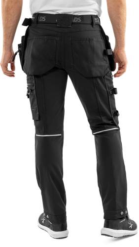Rückansicht einer Person, die schwarze taktische Hosen mit mehreren Taschen und Reißverschlüssen trägt, wobei Funktionalität und Langlebigkeit betont werden.