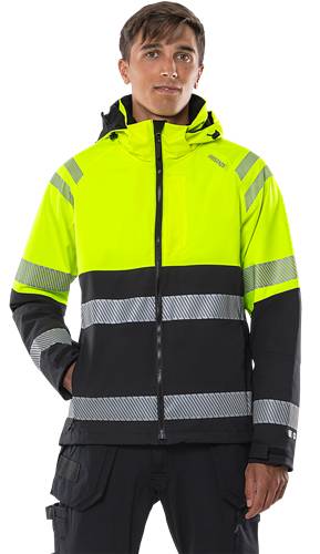 Person trägt eine Warnschutzjacke in Gelb und Schwarz mit reflektierenden Streifen, Hände in den Hosentaschen, dunkler Hintergrund.