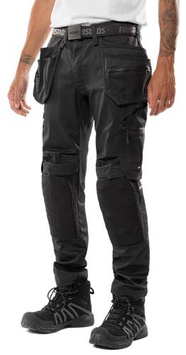 Eine Person, die schwarze Cargo-Hosen mit verstärkten Knien trägt, wobei Details der Taschen und robuster Stoff vor einem einfarbigen Hintergrund präsentiert werden.