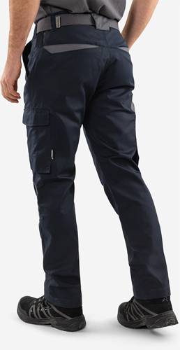 Eine Person trägt eine marineblaue Cargo-Hose mit seitlichen Taschen und steht vor einem einfarbigen Hintergrund.