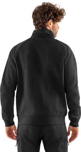 Eine Person, die von hinten zu sehen ist, trägt eine schwarze Jacke vor einem neutralen Hintergrund.