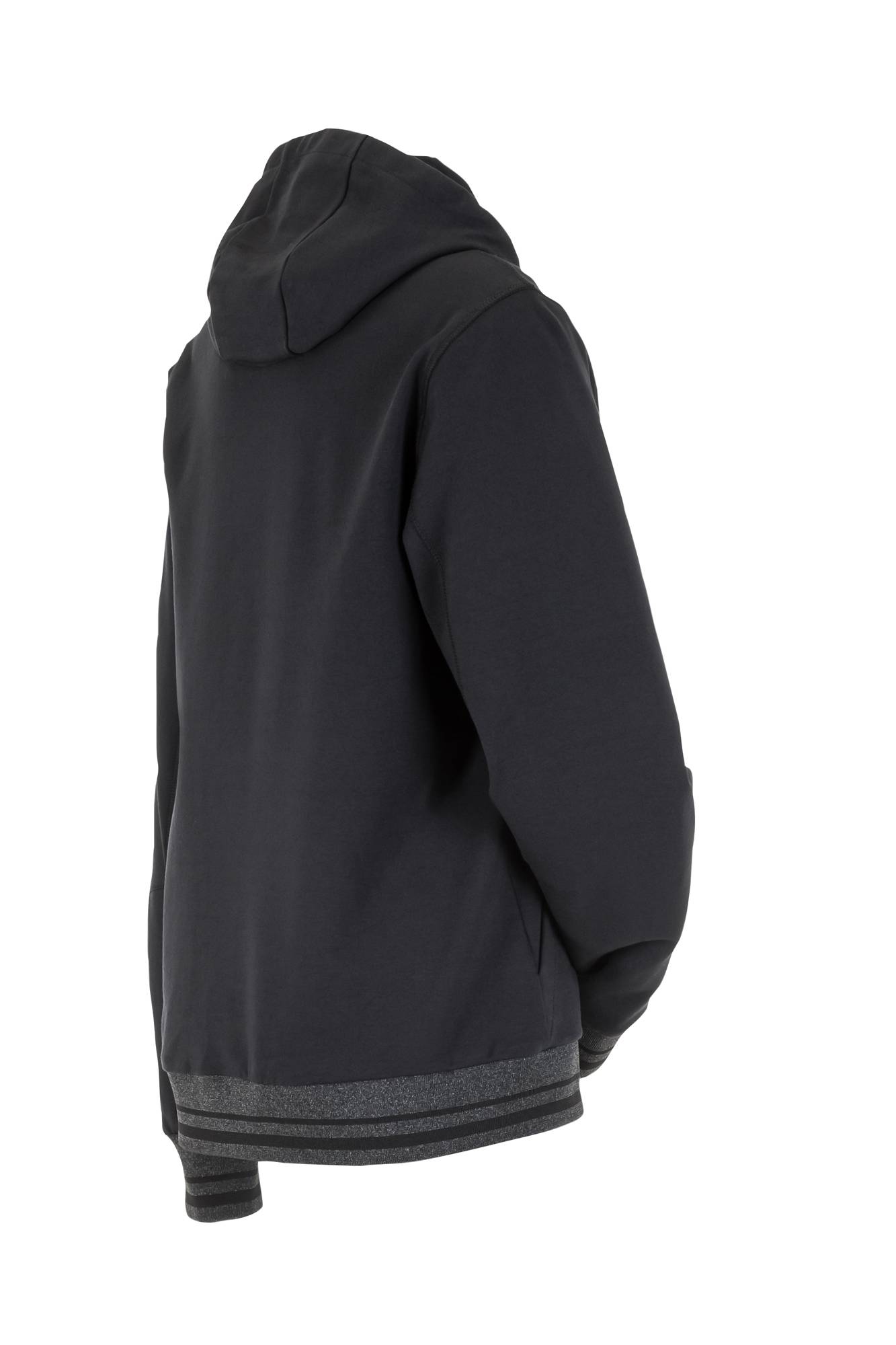 Eine Person in einem schwarzen Hoodie steht mit in den Taschen vergraben mit dem Rücken zu einer einfarbigen weißen Hintergrundwand.