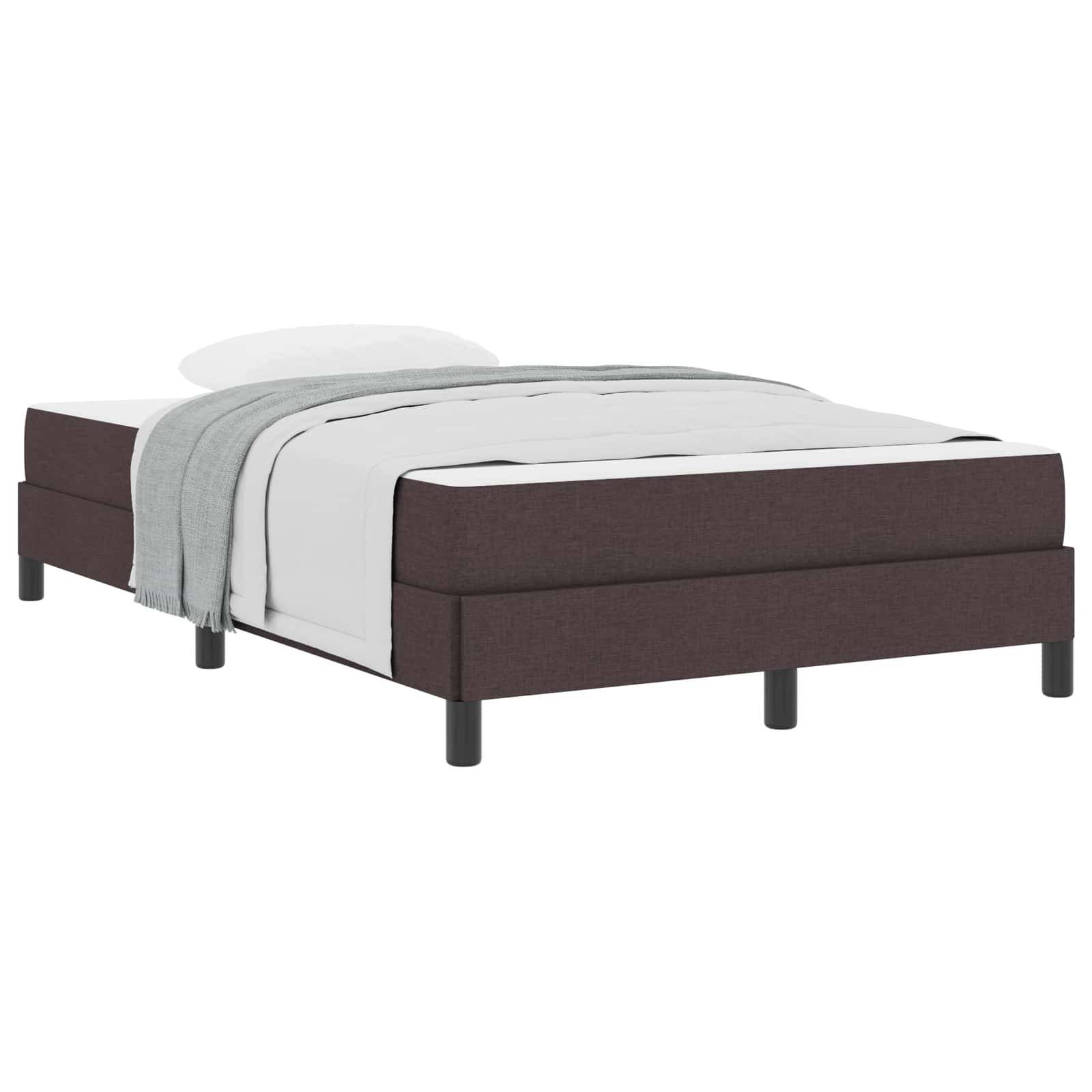 Ein einfaches Bett mit einem braunen gepolsterten Rahmen. Es hat weiße Bettwäsche und eine zusammengelegte graue Decke, die über einer Seite drapiert ist.