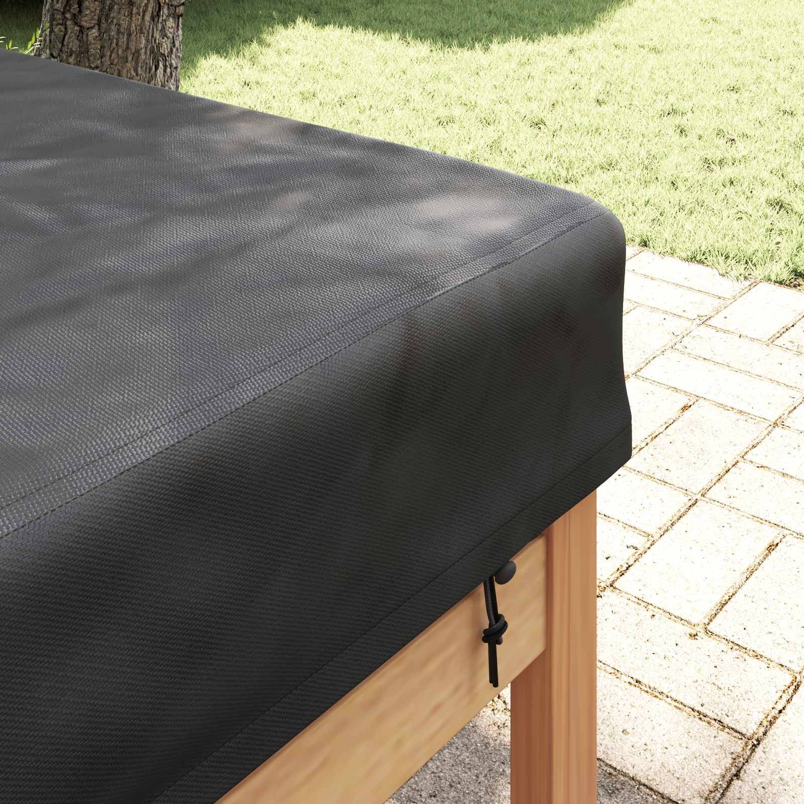 Eine schwarze Außentischdecke, die auf einem Holztisch befestigt ist, mit einem ordentlich gepflasterten Patio und einem grünen Rasen im Hintergrund.