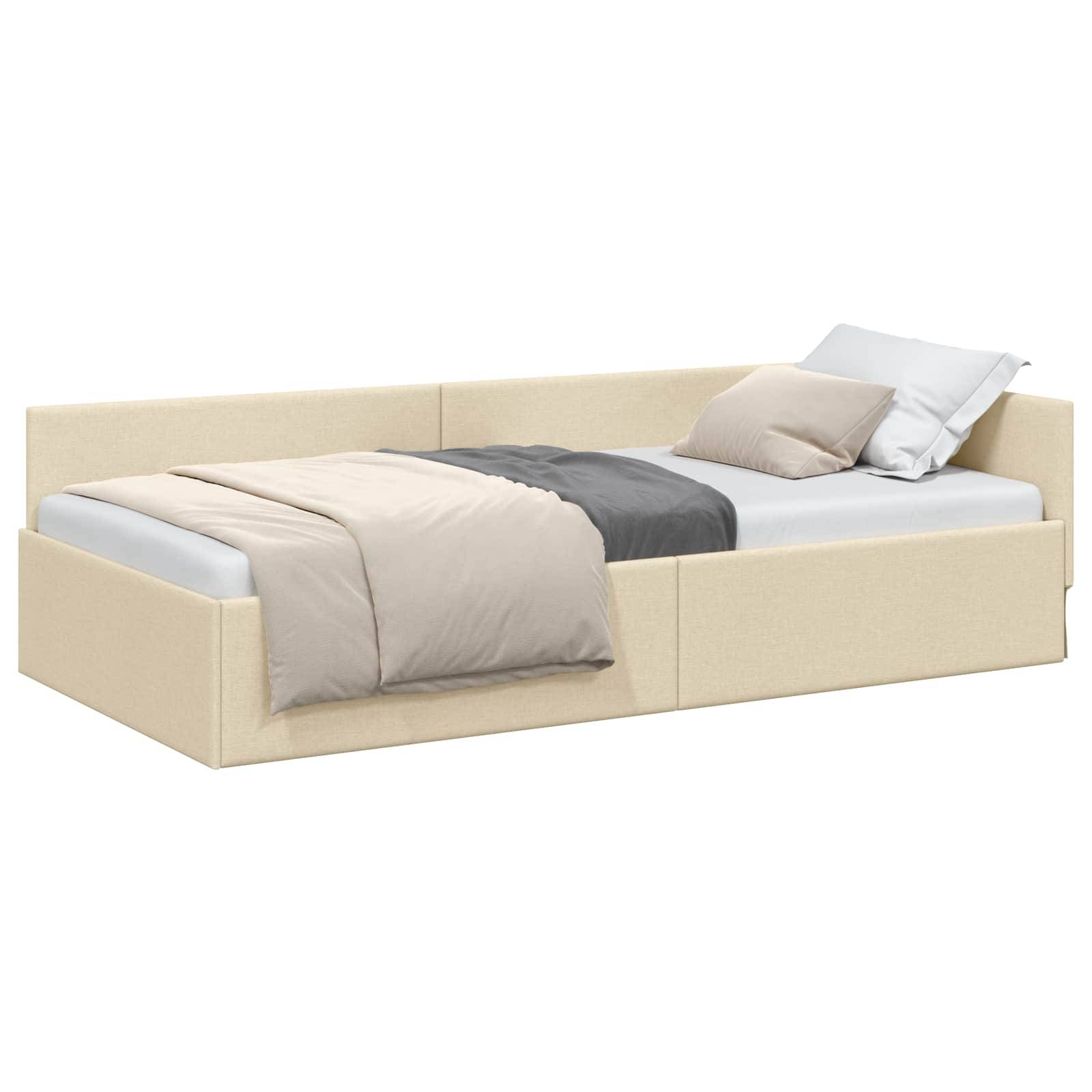 Ein beige gepolstertes Tagesbett mit Ausziehbett, ausgestattet mit einer weißen Matratze, hellgrauen und dunkelgrauen Kissen und einer hellbeigen Decke.