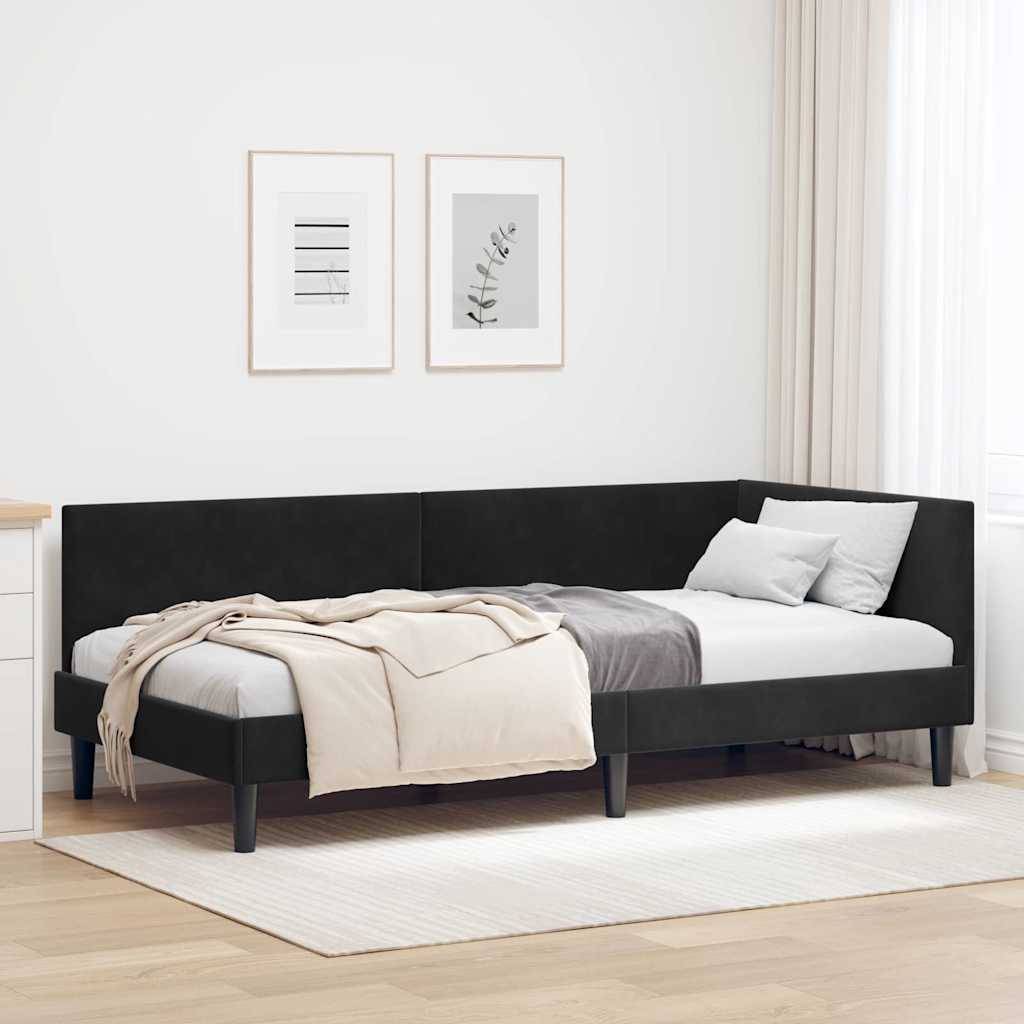 Ein schwarzes gepolstertes Eckbett mit weiß-grauer Bettwäsche, zwei gerahmte botanische Drucke an der Wand und transparente Vorhänge in einem hellen Raum.