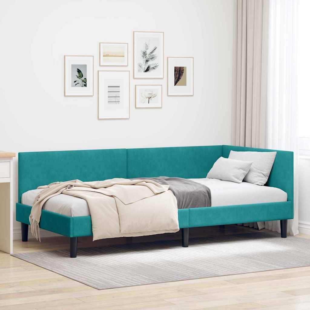 Ein Tagesbett mit tealblanem Polsterstoff mit beige- und grauen Kissen, das in einem hellen Raum aufgestellt ist. Eine Serie von gerahmten botanischen Kunstwerken hängt an der Wand darüber.
