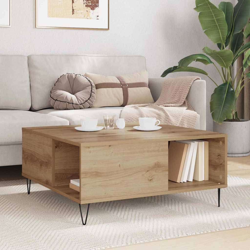 Modernes Wohnzimmer mit einem Couchtisch aus hellem Holz mit offener Lagerung, aufgestellt vor einem beigefarbenen Sofa mit Kissen, Büchern, Tassen und einer großen Topfpflanze.