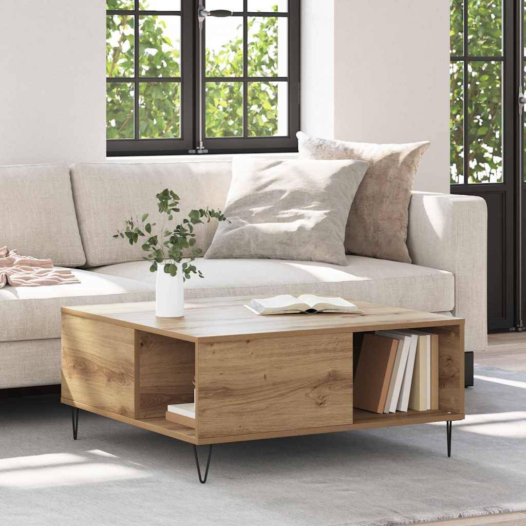 Helles Wohnzimmer mit einem beige Sofa und einem hölzernen Couchtisch mit einer Vase und einem Buch, mit Regalen und schwarzgerahmten Fenstern dahinter.