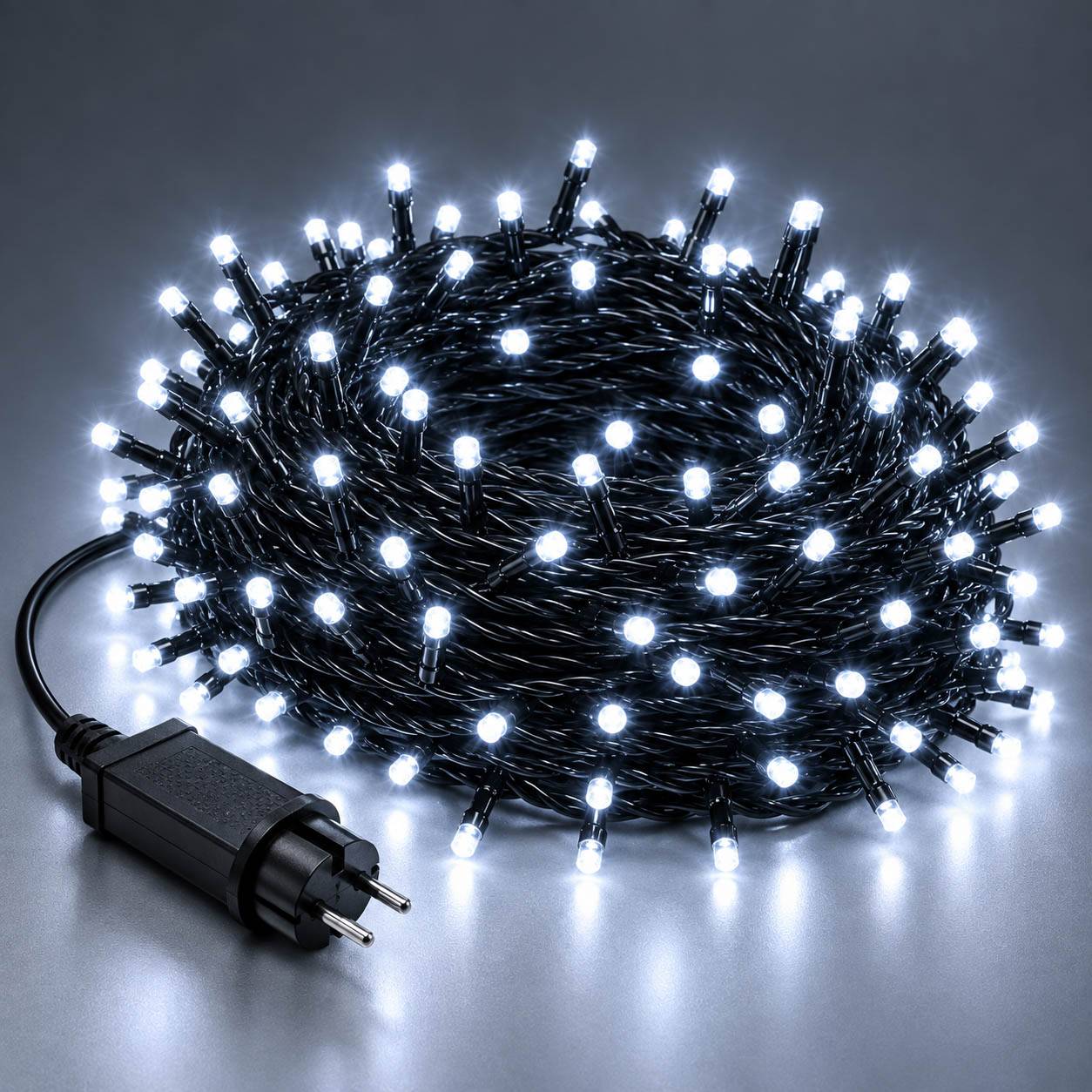 Eine aufgerollte Schnur mit weißen LED-Feenlichtern mit schwarzem Stecker auf einer grauen Oberfläche.
