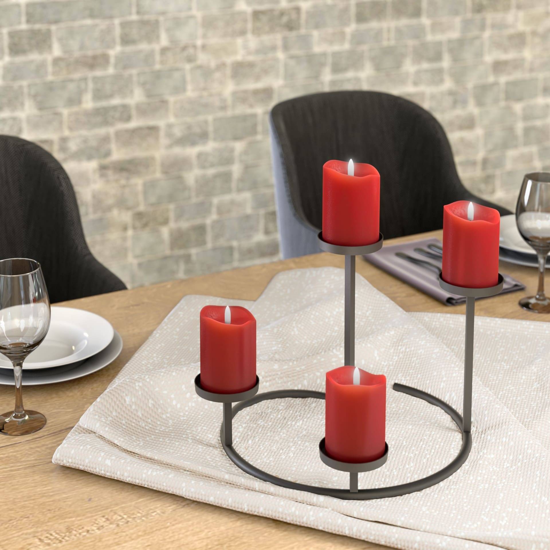 Ein Tisch ist mit einem weißen Tuch und Glaswaren eingedeckt und verfügt über ein Mittelstück aus vier roten Kerzen auf einem modernen Metallständer.