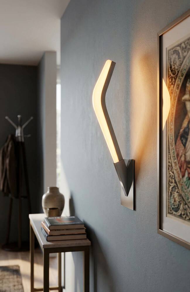 Moderne Wandleuchte mit leuchtender gebogener LED-Leuchte an einer grauen Flurwand neben einem gerahmten Kunstwerk und einem schmalen Konsolentisch mit Büchern und einer Vase.