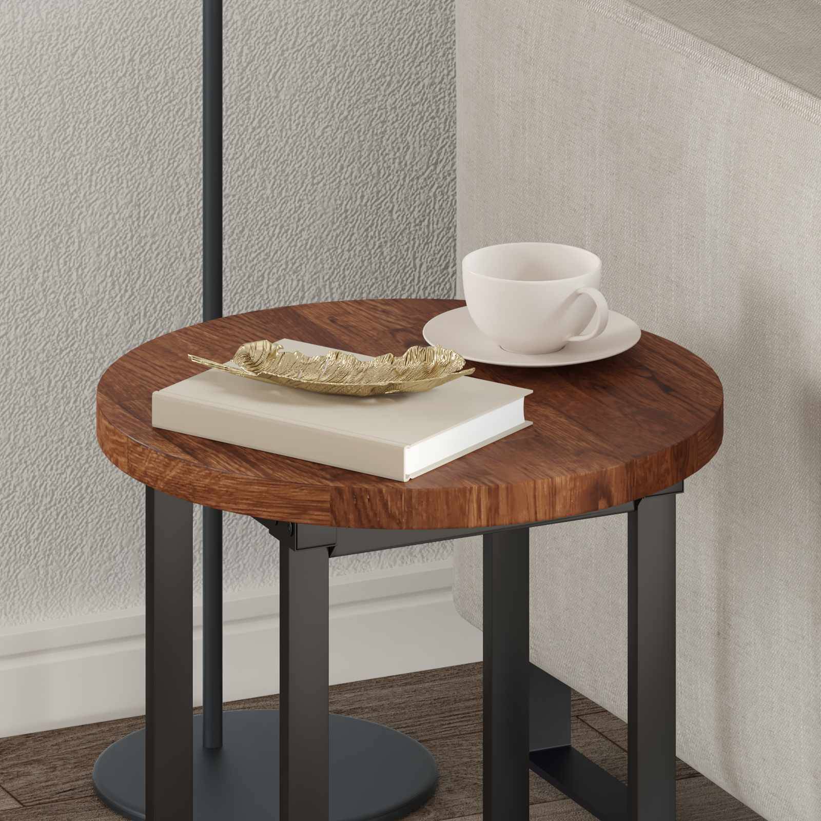 Ein kleiner runder Holztisch steht an einer grauen Wand und trägt eine weiße Teetasse auf einem Unterteller, ein kleines Buch und eine dekorative blattförmige Schale.
