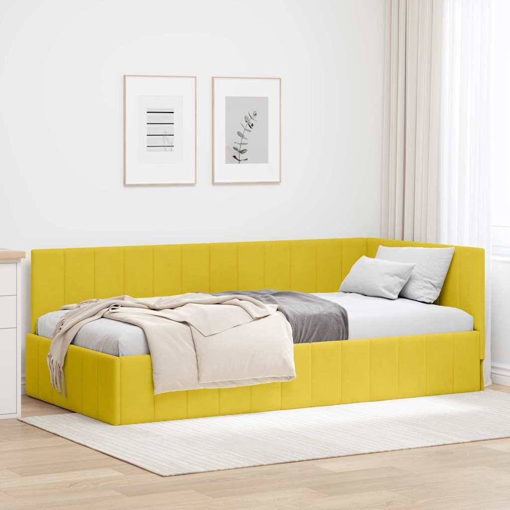 Ein minimalistisches Zimmer mit einem gelben Eckschlafsofa mit grauen Kissen und einer beigen Decke, weißen Wänden und zwei gerahmten botanischen Drucken.