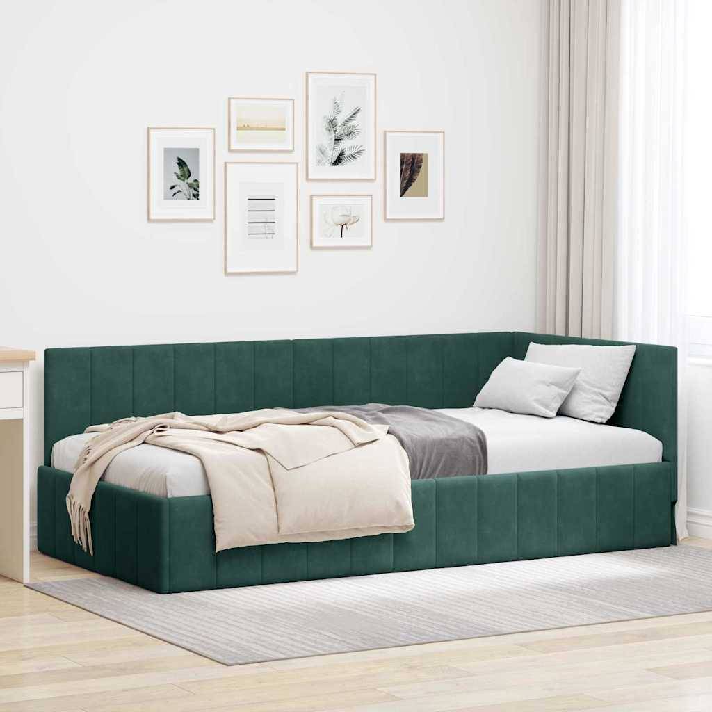 Ein modernes grünes Eckbett in einem hellen Zimmer, mit einer beigen Decke und weißen Kissen. Sechs gerahmte Kunstwerke hängen an den weißen Wänden.